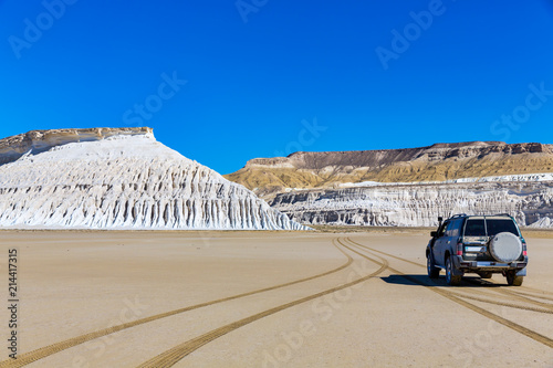 The wonderful views of the steep white cliffs and Tuzbair salt dry lake seen from the SUV driving toward the center of salt dry lake, in Mangystau, Kazakhstan photo
