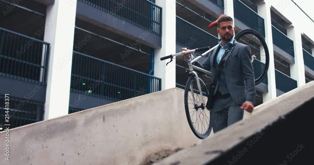 TRACKING Handsome young adult man wearing suit holding his classic bicycle on the shoulder while walking downstairs. 4K UHD TRACKING Handsome young adult man wearing suit holding his classic bicycle on the shoulder while walking downstairs. 4K UHD