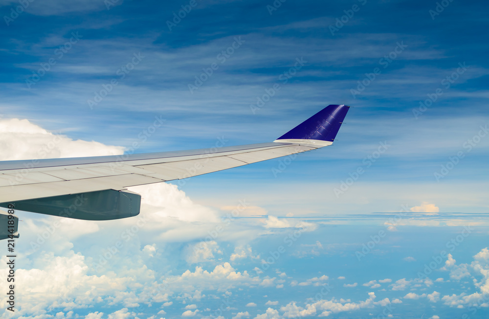 Fototapeta premium Wing of airplane flying over the cloudy sky.