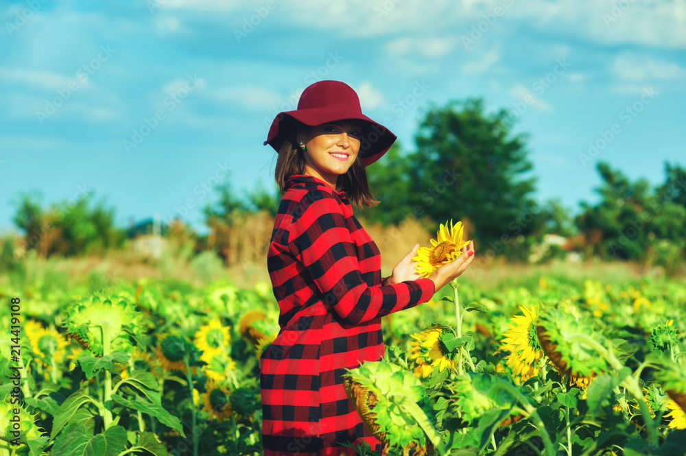 Young woman in a wide-brimmed hat in a field with sunflowers