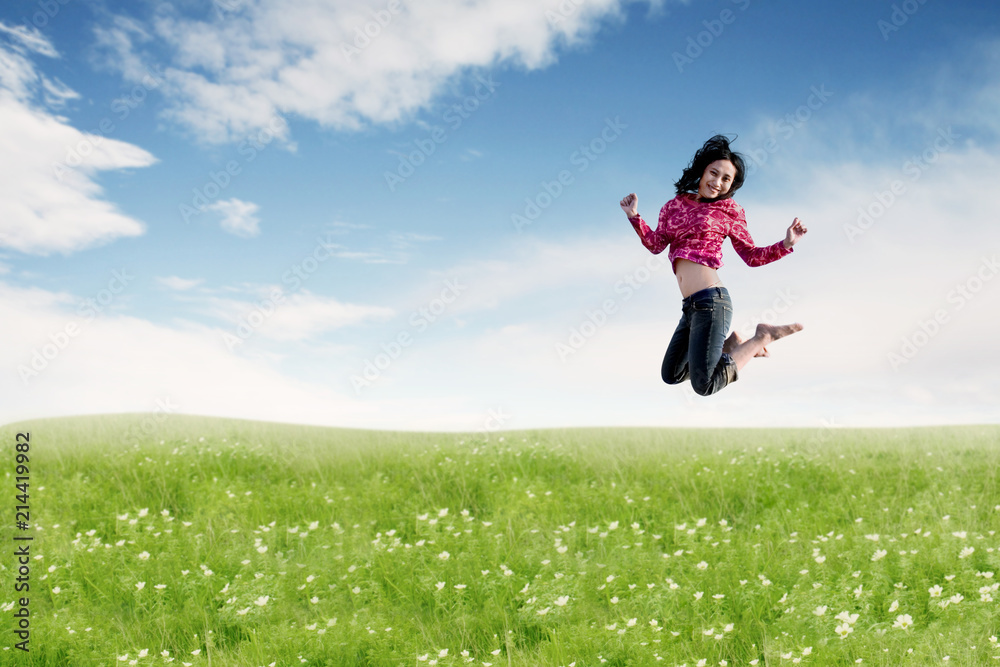 Carefree Asian woman making a big jump on meadow. Carefree Asian woman making a big jump on meadow.