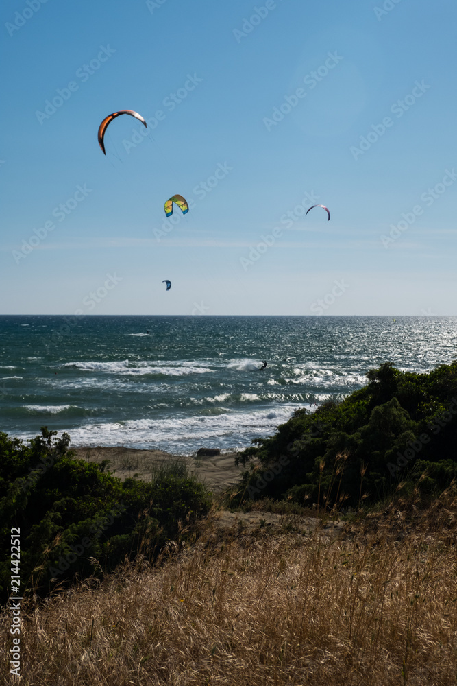 Vertical view from the sand dunes of kitesurfing under a bright sun on a blue sky. Vertical view from the sand dunes of kitesurfing under a bright sun on a blue sky.