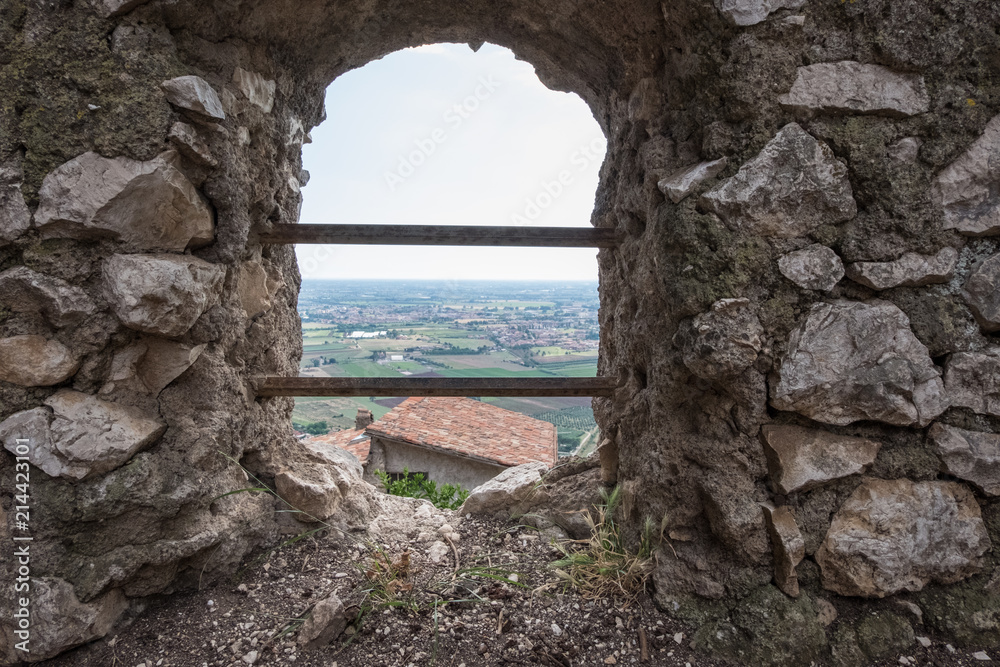 Wallpaper background of landscape view from a hole on an antique stone wall in a medieval town. Sermoneta. Italy. No people.