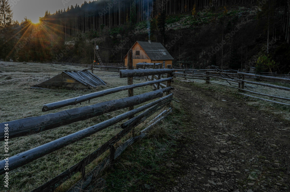 Road near the wooden fence to the wooden house. Autumn, frozen grass, Carpathians