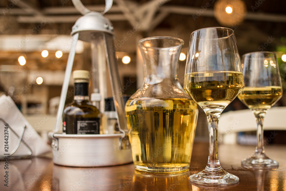 Pouring white wine into the glass against wooden table Pouring white wine into the glass against wooden table
