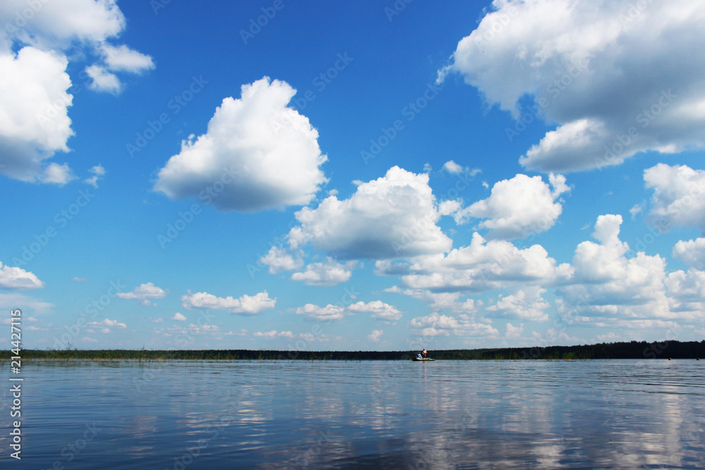 Lake Vysokinskoye in the summer, with the reflection of white clouds in the water. Leningrad Region, Russia.