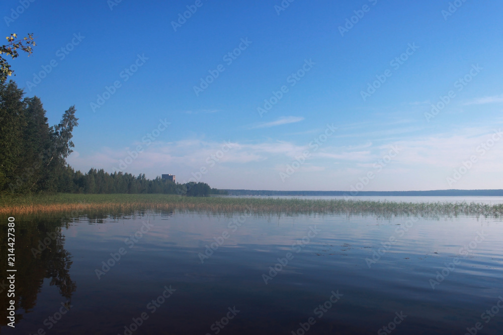 Lake Vysokinskoye in the summer, with the reflection of white clouds in the water. Leningrad Region, Russia.