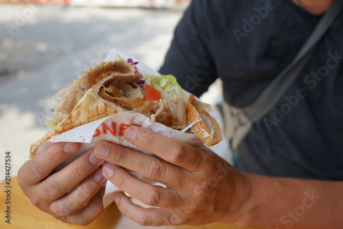 Man eating Berliner Döner Kebap, Berlin Doener Kebab, street food.