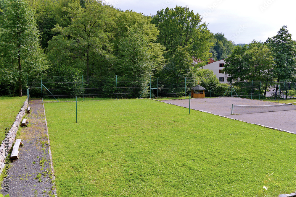 Tennis court with two courts: one with a grass cover, and the second with asphalt