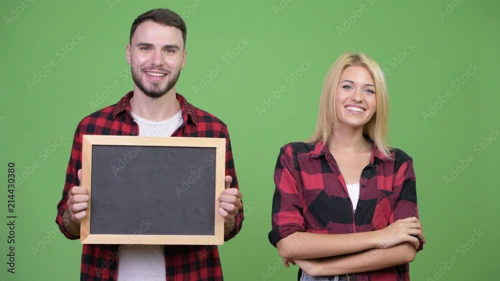 Young couple holding blackboard and arms crossed together Young couple holding blackboard and arms crossed together