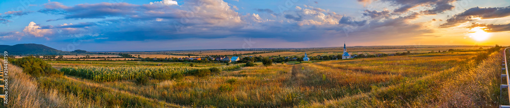 panorama of a field near a road in the background of a village with a church panorama of a field near a road in the background of a village with a church