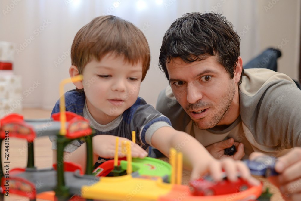 Obraz premium Father and son are playing with toy cars. Happy family playing with toys