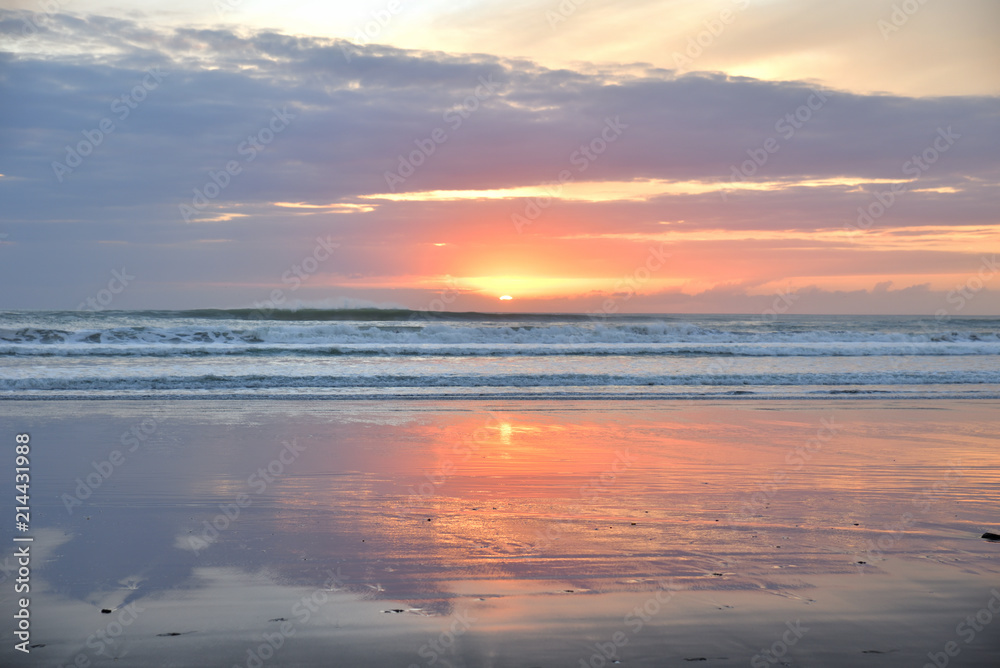 Spiegelung im Wasser am Sandstrand in Muriwai Beach