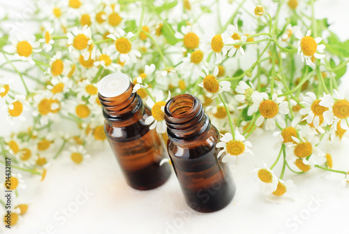 Essential oil of chamomile. Dropper bottles with holistic flowers white table, light background, angle. 