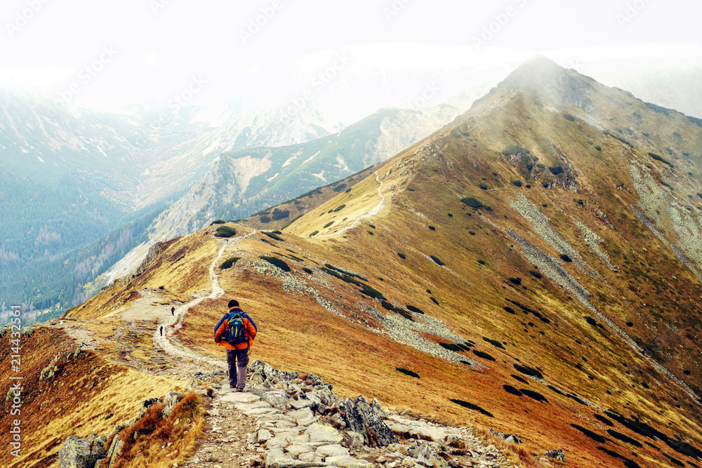 A man with a backpack walking along a path in the mountains