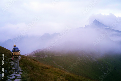 A man with a backpack walking along a path in the mountains