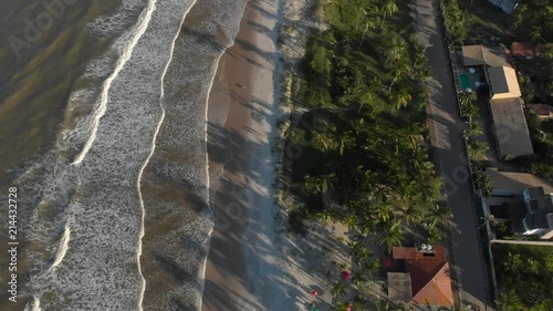 flight over beach restaurant while waves hit shore. canavieiras, bahia, brazil