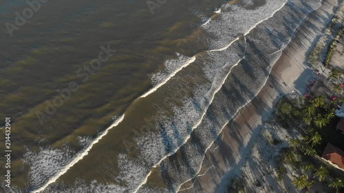 Wide shot of waves hitting shore with palm trees shade. canavieiras, bahia, brazil