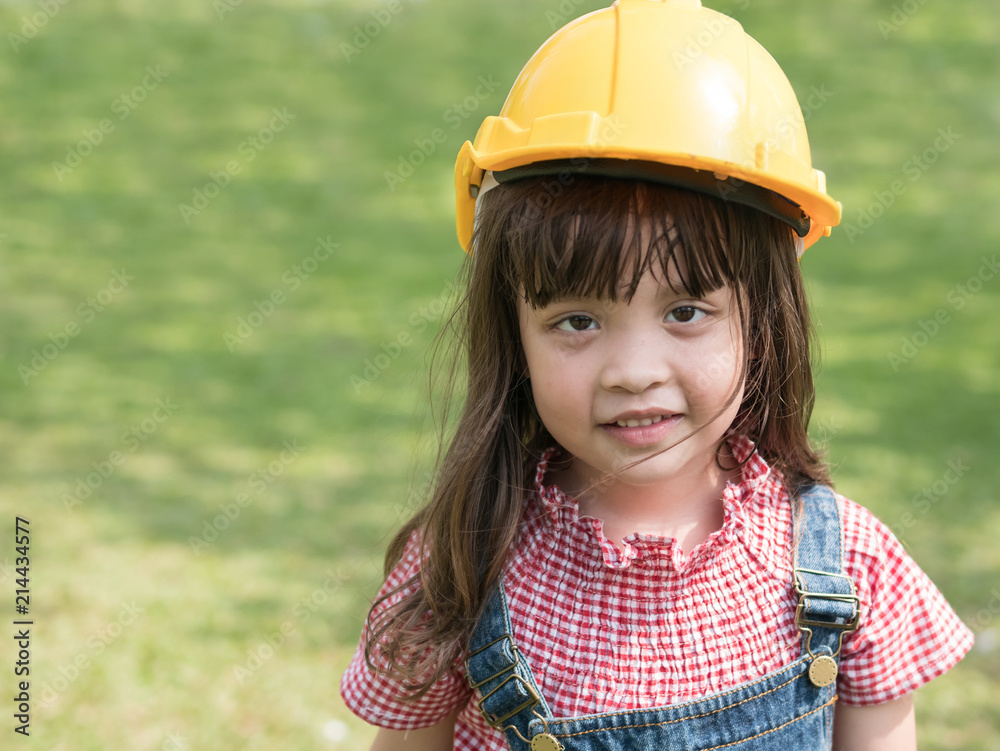 Cute little girl wearing yellow engineer helmet at the park. Cute little girl wearing yellow engineer helmet at the park.