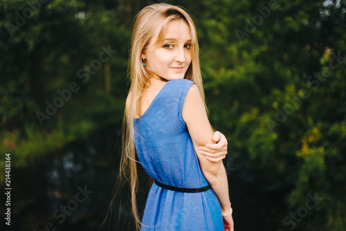 Young beautiful girl with long hair in a blue dress outdoors, woman in nature, professional make-up and hairstyle © Pavel