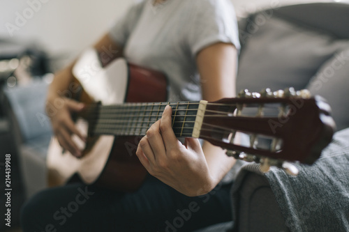 A young girl learns to play guitar. Woman's hands playing acoustic guitar.