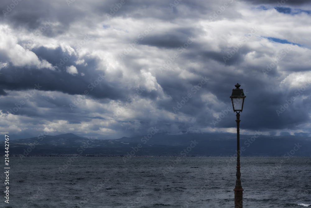 A lonely lantern against the background of the sea and the dramatic sky