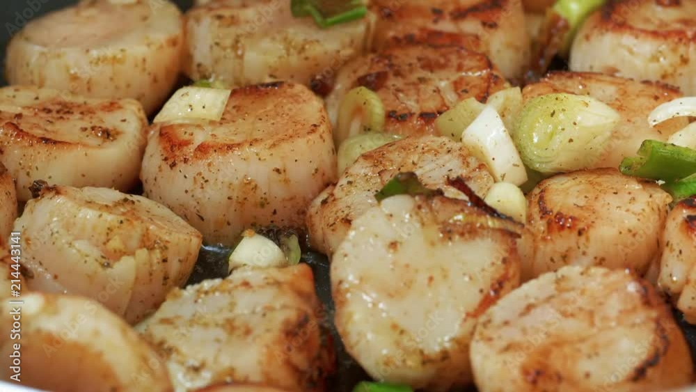 Delicious scallops are frying with the butter and herbs in UHD Delicious scallops are frying with the butter and herbs in UHD