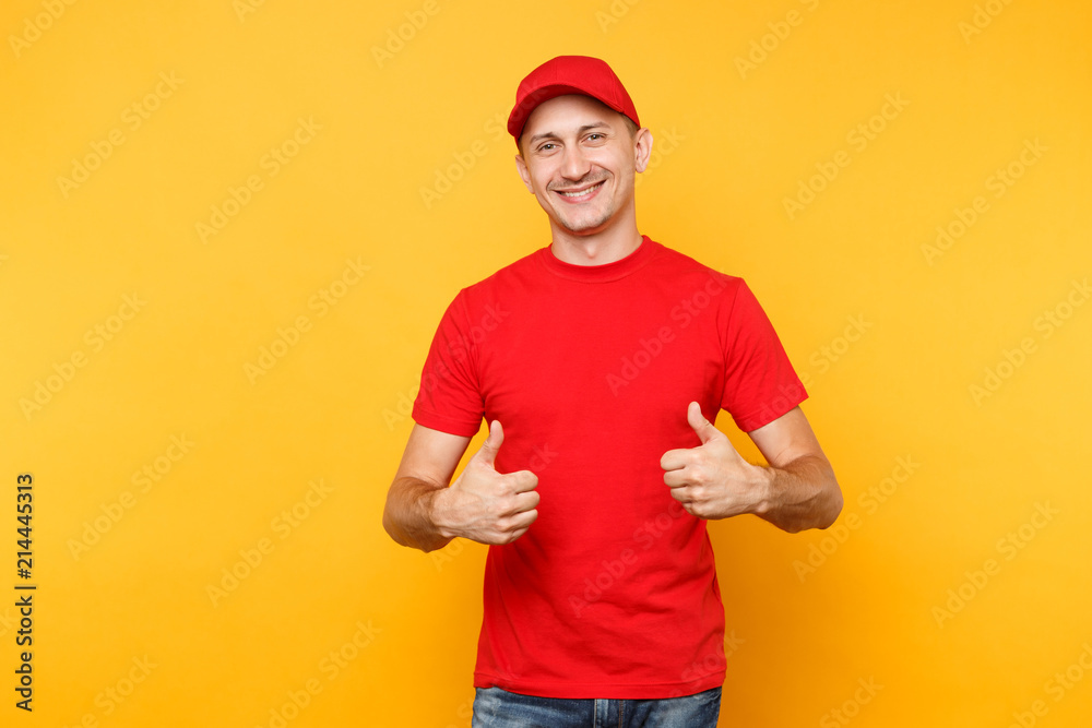 Delivery man in red uniform isolated on yellow orange background. Professional smiling male employee in cap, t-shirt working as courier or dealer showing thumbs up gesture. Service concept. Copy space