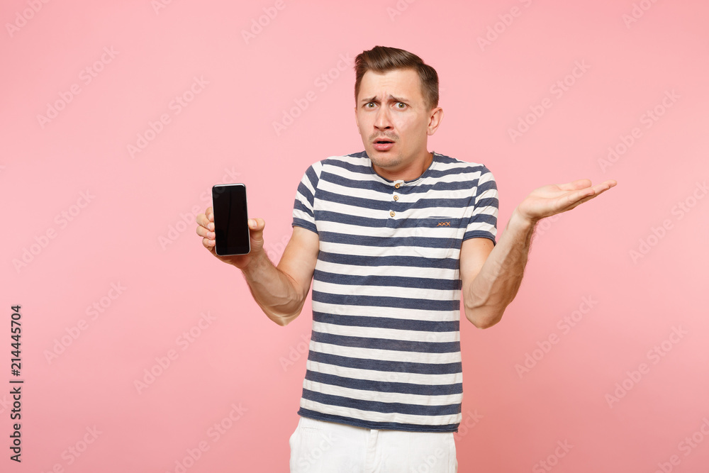 Portrait of man in striped t-shirt showing mobile phone camera with blank black empty screen copy space isolated on trending pastel pink background. People sincere emotions concept. Advertising area. Portrait of man in striped t-shirt showing mobile phone camera with blank black empty screen copy space isolated on trending pastel pink background. People sincere emotions concept. Advertising area.