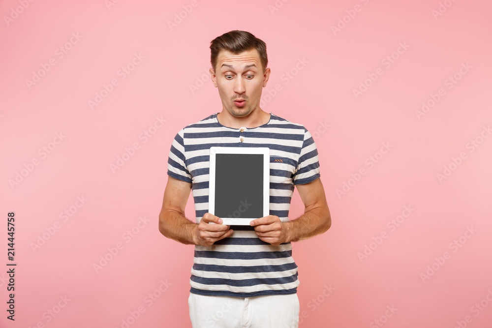 Portrait of young man holding tablet computer with blank black empty screen display touchscreen copy space isolated on trending pastel pink background. Technology lifestyle concept. Advertising area. Portrait of young man holding tablet computer with blank black empty screen display touchscreen copy space isolated on trending pastel pink background. Technology lifestyle concept. Advertising area.