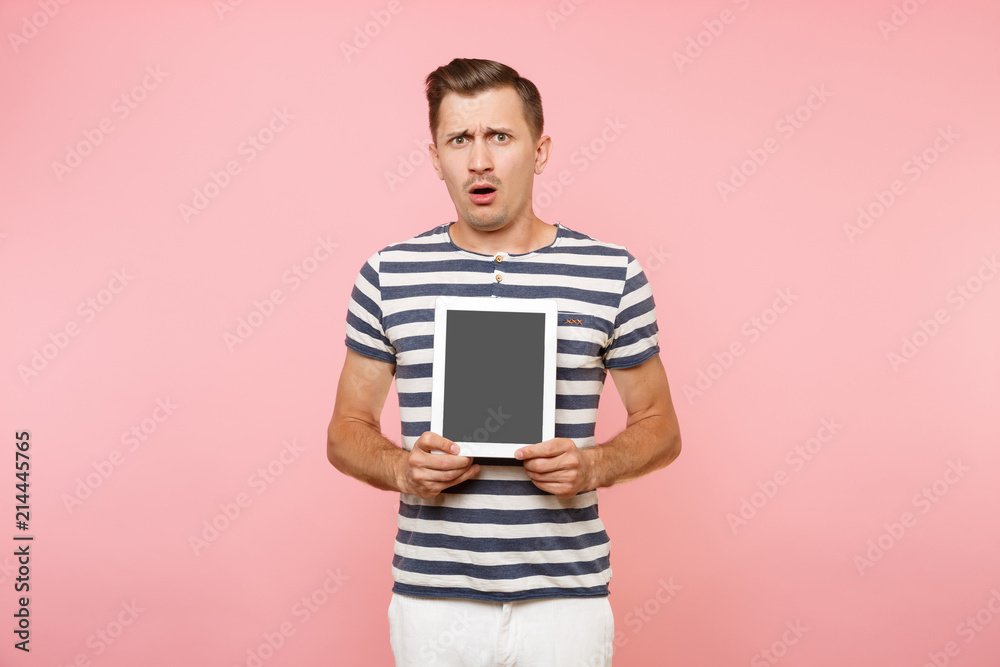 Portrait of young man holding tablet computer with blank black empty screen display touchscreen copy space isolated on trending pastel pink background. Technology lifestyle concept. Advertising area. Portrait of young man holding tablet computer with blank black empty screen display touchscreen copy space isolated on trending pastel pink background. Technology lifestyle concept. Advertising area.