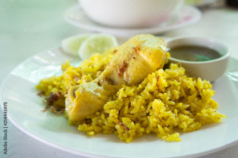 Chicken biryani (chicken rice curry with coconut) with spicy sauces on white dish in vintage white wooden table. For food.