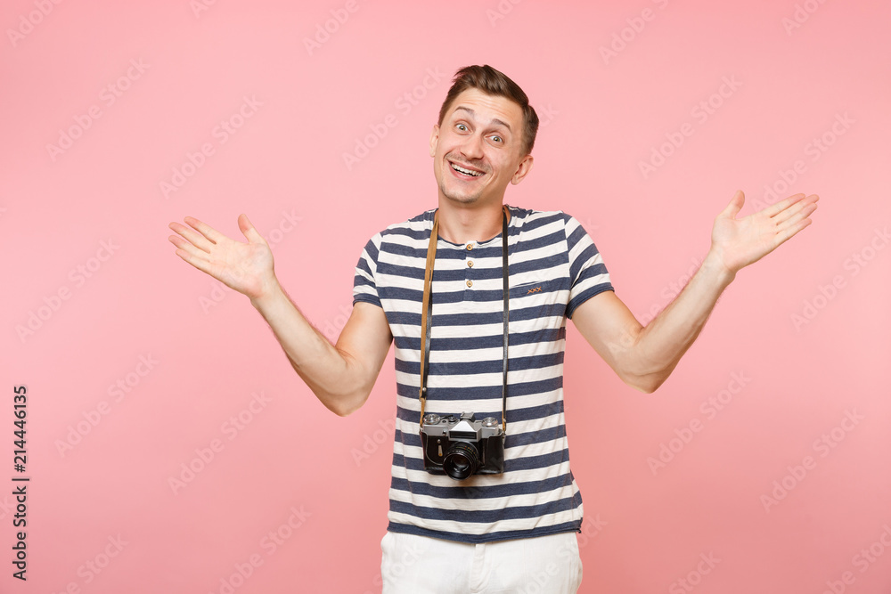 Portrait of smiling young photographer man wearing striped t-shirt take pictures on retro vintage photo camera isolated on trending pastel pink background. People sincere emotions lifestyle concept. Portrait of smiling young photographer man wearing striped t-shirt take pictures on retro vintage photo camera isolated on trending pastel pink background. People sincere emotions lifestyle concept.