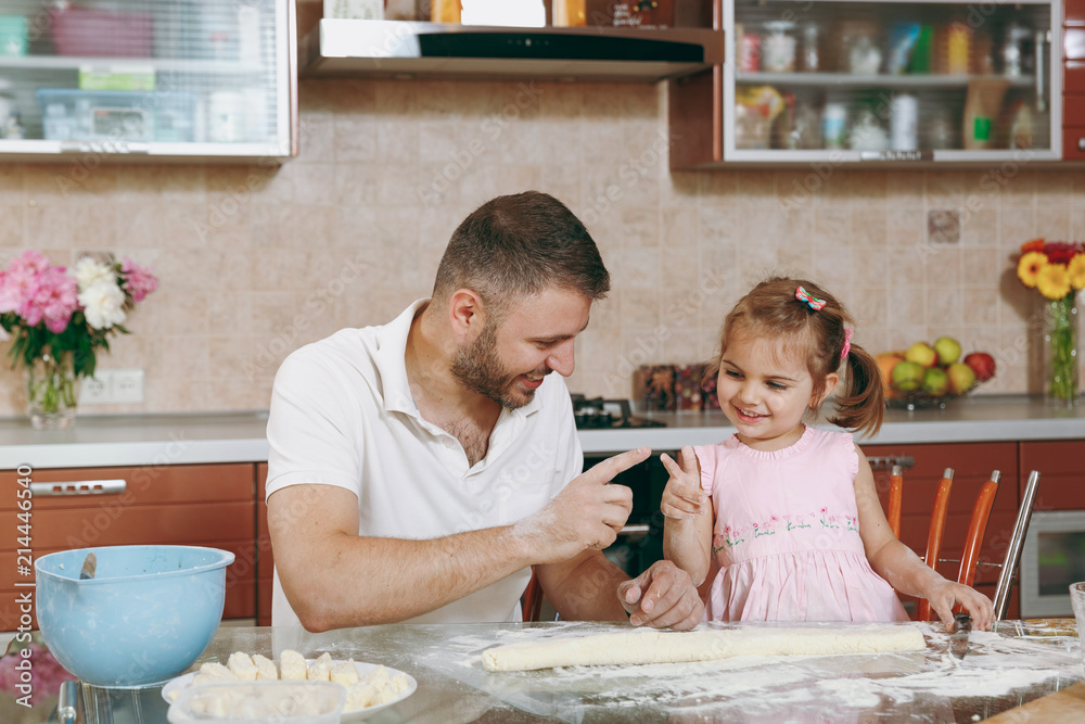 Little kid girl helps man to cook lazy dumplings, play in light kitchen at table. Happy family dad, child daughter cooking food in weekend morning at home. Father's day holiday. Parenthood, childhood. Little kid girl helps man to cook lazy dumplings, play in light kitchen at table. Happy family dad, child daughter cooking food in weekend morning at home. Father's day holiday. Parenthood, childhood.