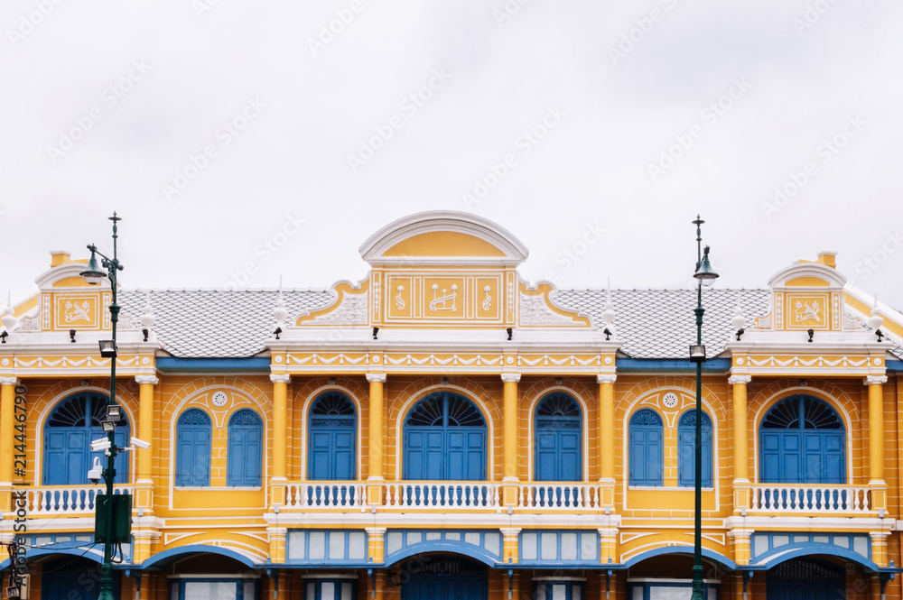 Facade of yellow colonial building with blue doors and windows in Bangkok old town