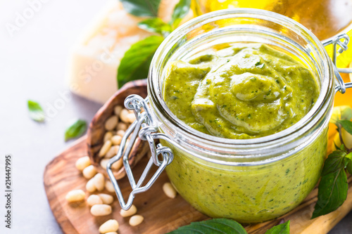 Pesto sauce in glass jar and ingredients. 