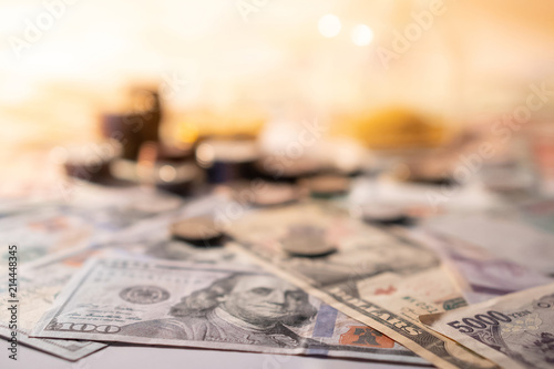 Obraz na płótnie Various of international money coin and banknote with blurred hourglass in the background