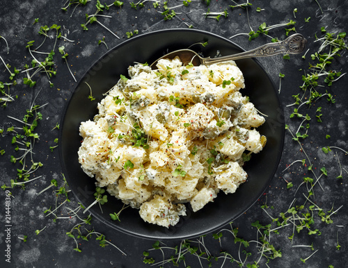 фотографія Warm potato salad with gherkins in a black plate