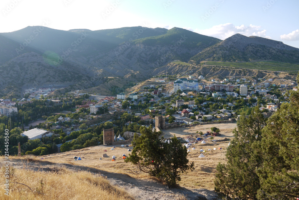 sandy slopes on the background of a cozy town and high mountains covered with grass