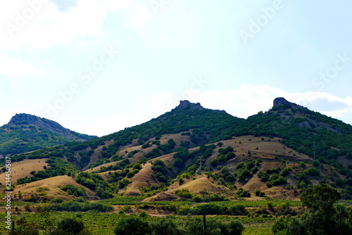 high rocky slopes covered with grass on the background of the cloudy sky