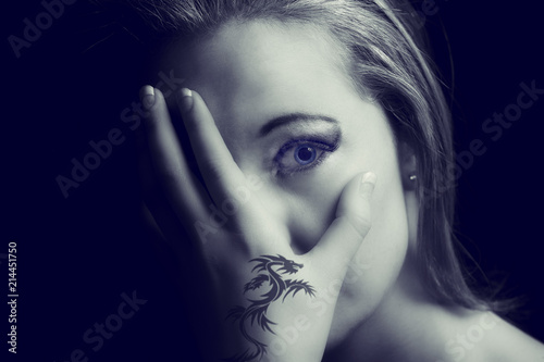 Portrait of a scared woman with a tattoo hand on her face artistic conversion