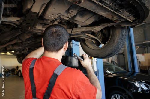 Profecional car mechanic changing motor oil in automobile engine at maintenance repair service station in a car workshop. photo