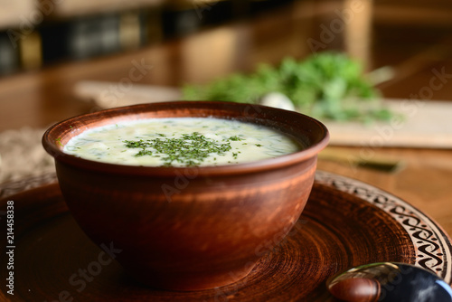 Summer yoghurt cold soup with radish, cucumber, and dill on wooden table. Okroshka.