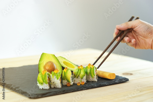 japanese avocado sushi on black slate stone and wood table