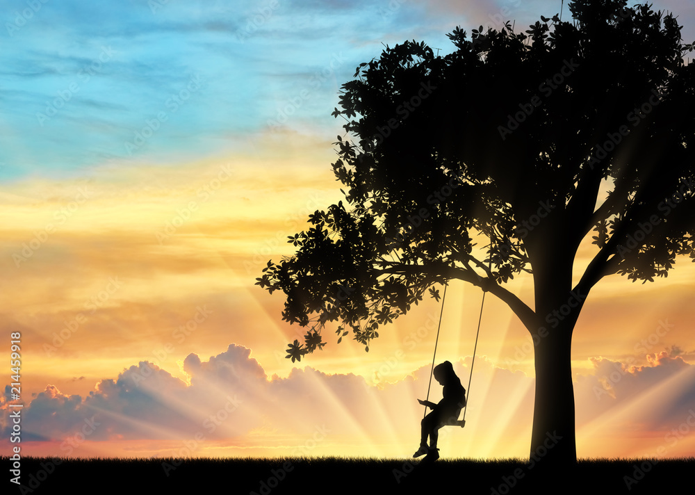 Silhouette of little girl reading book sitting on swing.