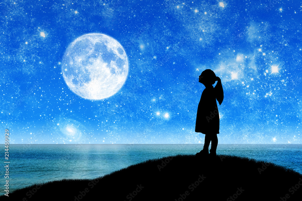 Silhouette, little girl child standing on a hill by the sea looking at the starry sky.