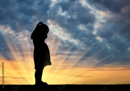 Silhouette of sad little baby girl crying against sunset background