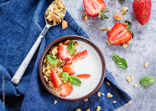 Breakfast with yogurt, granola of muesli and strawberries on gray concrete table background. Healthy Vegan Clean Diet Food Concept. Top view, copy space, flat lay photo