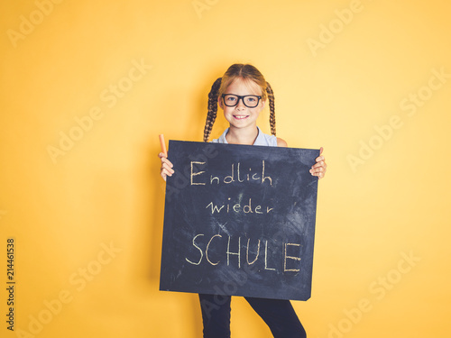 schulkind hält schild mit der aufschrift endlich wieder schule vor gelbem hintergrund photo