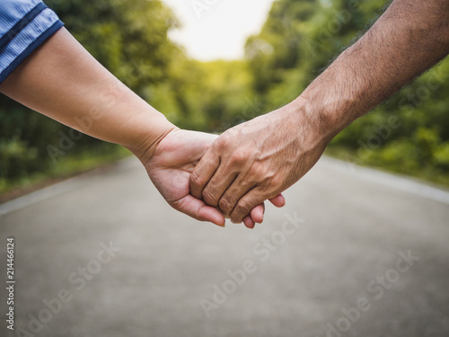 Couple holding hands on the road and forest blurred background. Love & Go together Concept.